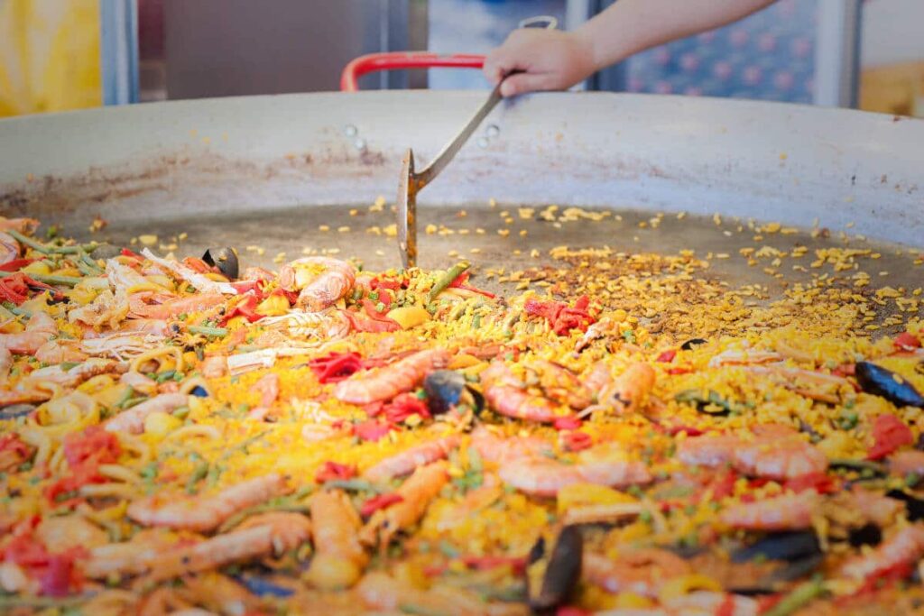 What is the ideal size of a paella pan for the number of servings to be prepared?